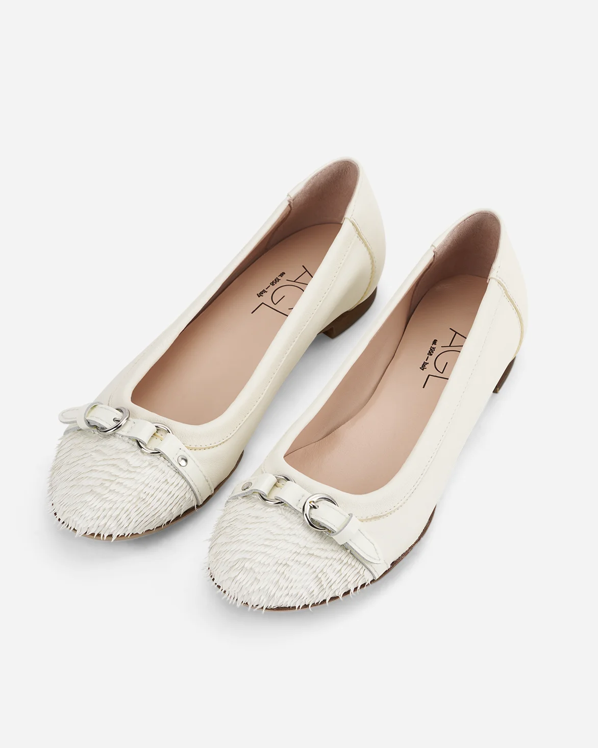 Pair of ivory pointed flats with textured toes prepared for an e-commerce catalog