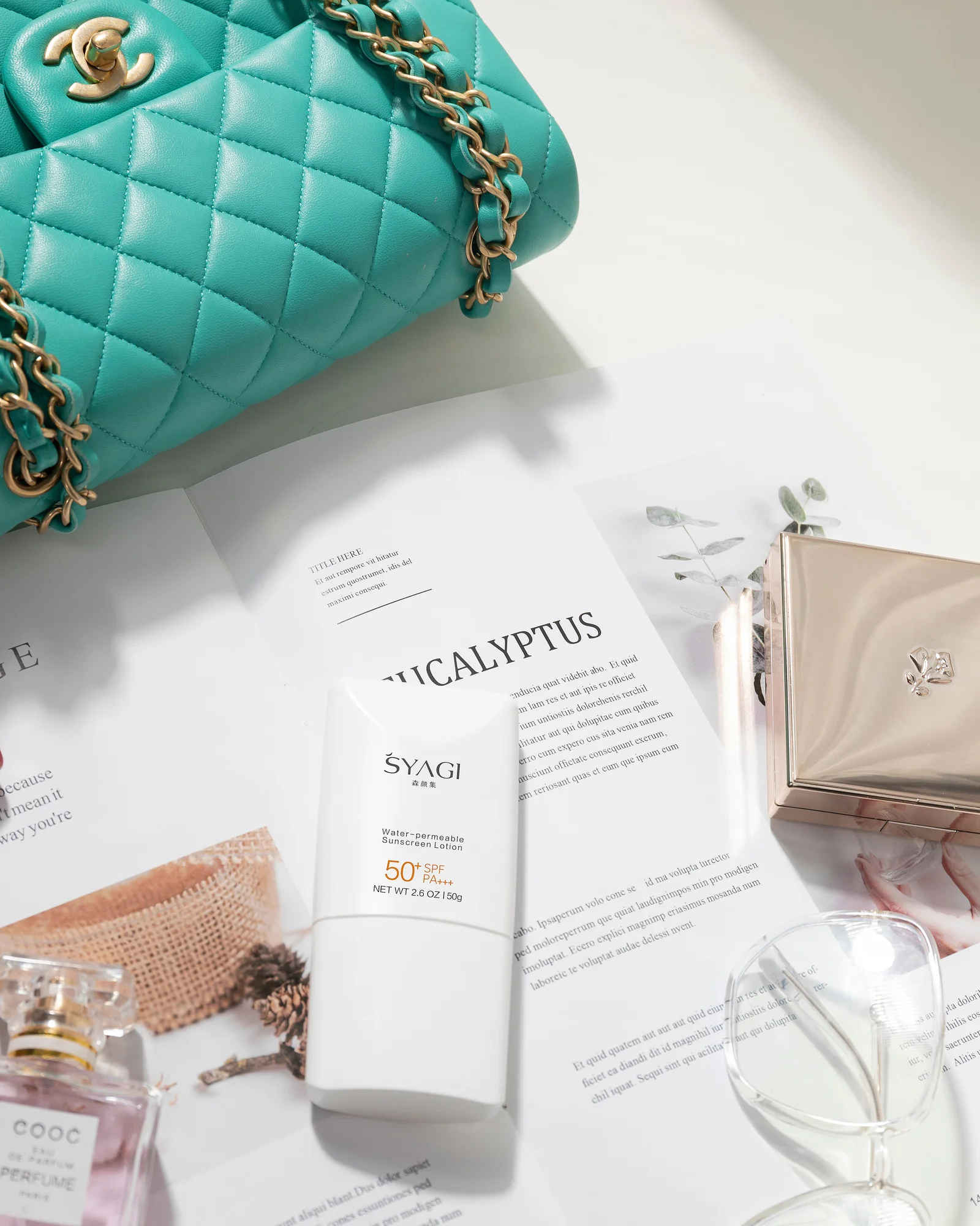 Turquoise quilted handbag and perfume styled together for an e-commerce flat lay