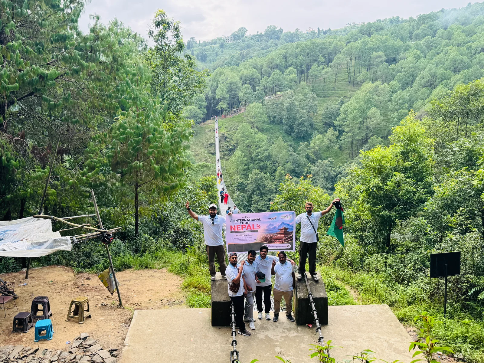 Studio Click House team holding official tour banner at Nepal suspension bridge