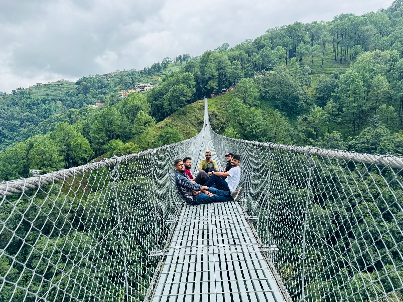 Panoramic view of suspension bridge spanning across mountain valley