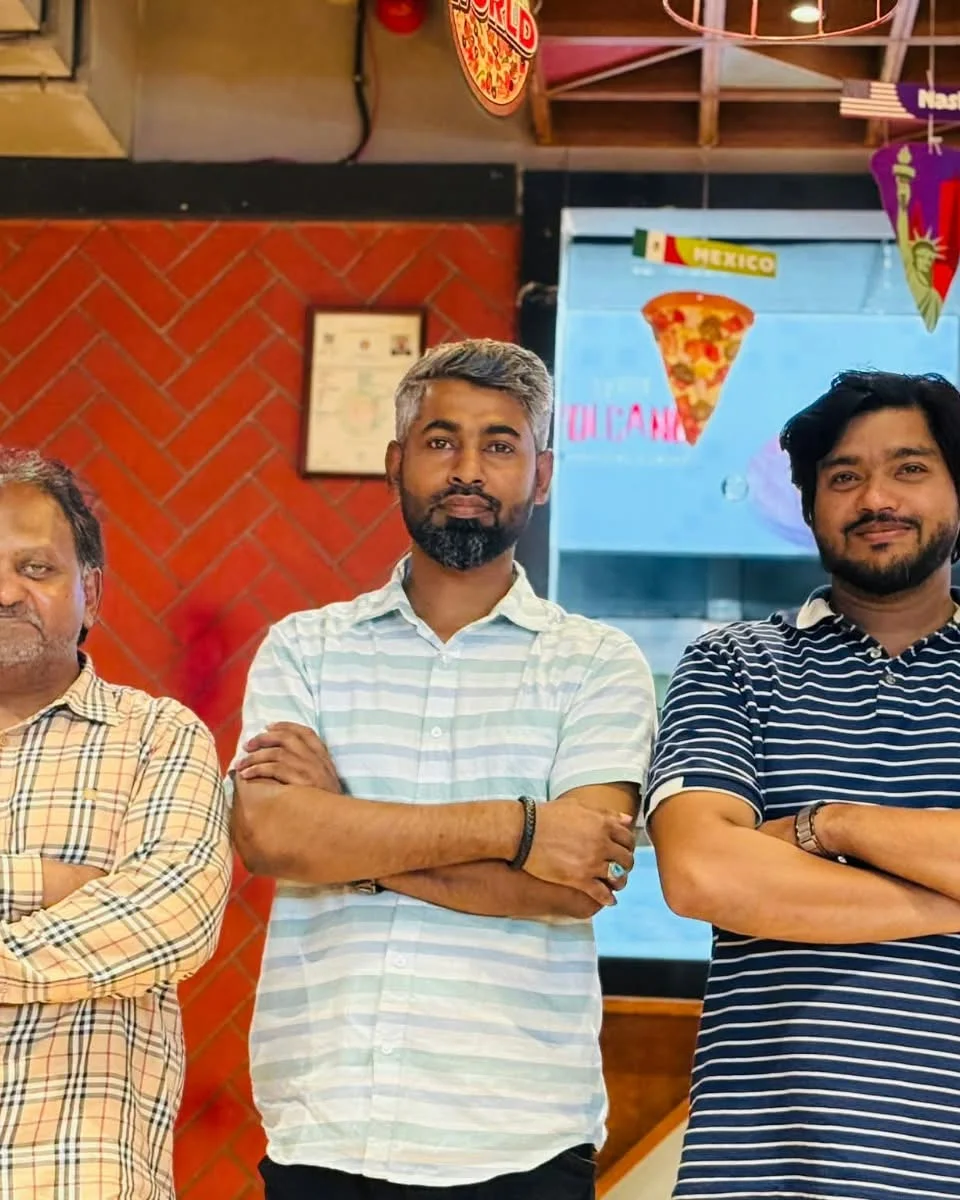 Colleagues smiling for group portrait during studio pizza party