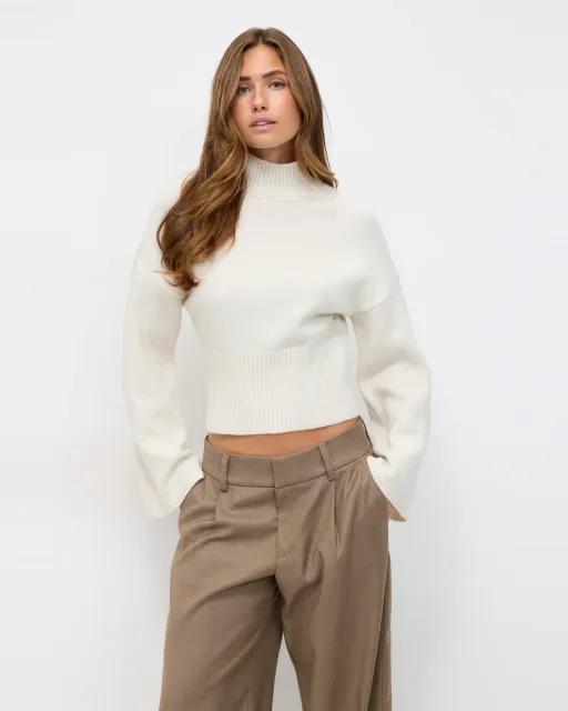 Fashion model wearing a cream knit turtleneck sweater